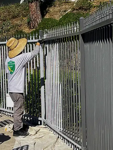 Crew worker painting metal fence